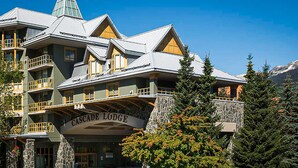 En byggnad med flera våningar, balkonger och en fasad av sten, med skylten ”Cascade Lodge”.