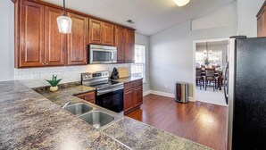 A kitchen with wooden cabinets, a granite countertop, stainless steel sink, and a black refrigerator. - Work-friendly Madison Home Near Research Park (Madison)