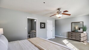 A bedroom with a bed, a ceiling fan, a dresser, and a door leading to another room. - Work-friendly Madison Home Near Research Park (Madison)