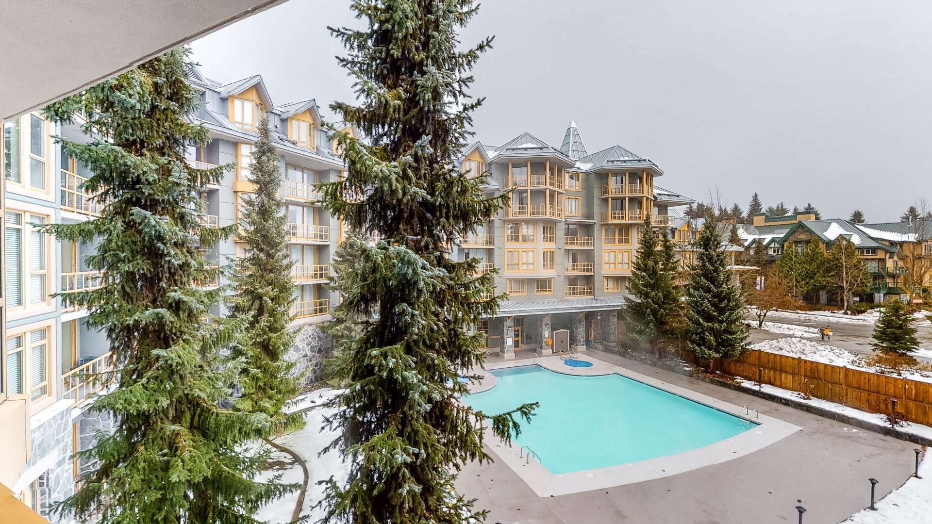 Un hôtel à étages, doté d’une piscine et entouré d’arbres à feuilles persistantes.