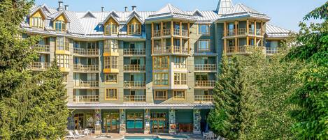 Un hotel de varios pisos con área de piscina, con balcones, un spa y vista a la montaña.