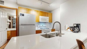 Une cuisine moderne avec des appareils électroménagers blancs, des armoires en bois et un évier en acier inoxydable.