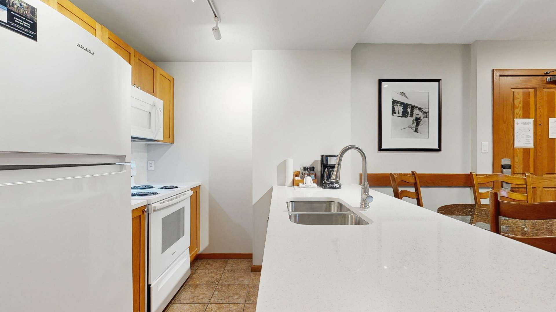A modern kitchen with white cabinets, a built-in oven, a stove, and a large island with a sink.