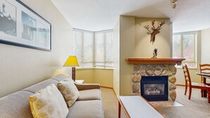 Ein Wohnzimmer mit Kamin, einer Couch, einem Tisch und einer Lampe.