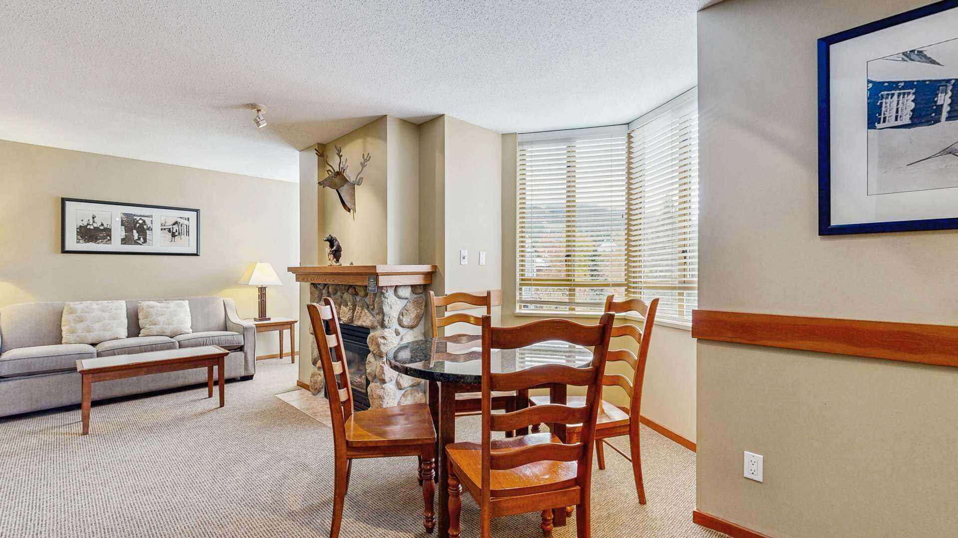 Ein Wohnzimmer mit Kamin, einem Esstisch mit Stühlen, einer Couch und einem gerahmten Bild an der Wand.