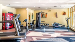 Ein Fitnessraum mit Cardiogeräten, Krafttrainingsgeräten und einem Coca-Cola-Kühlschrank.