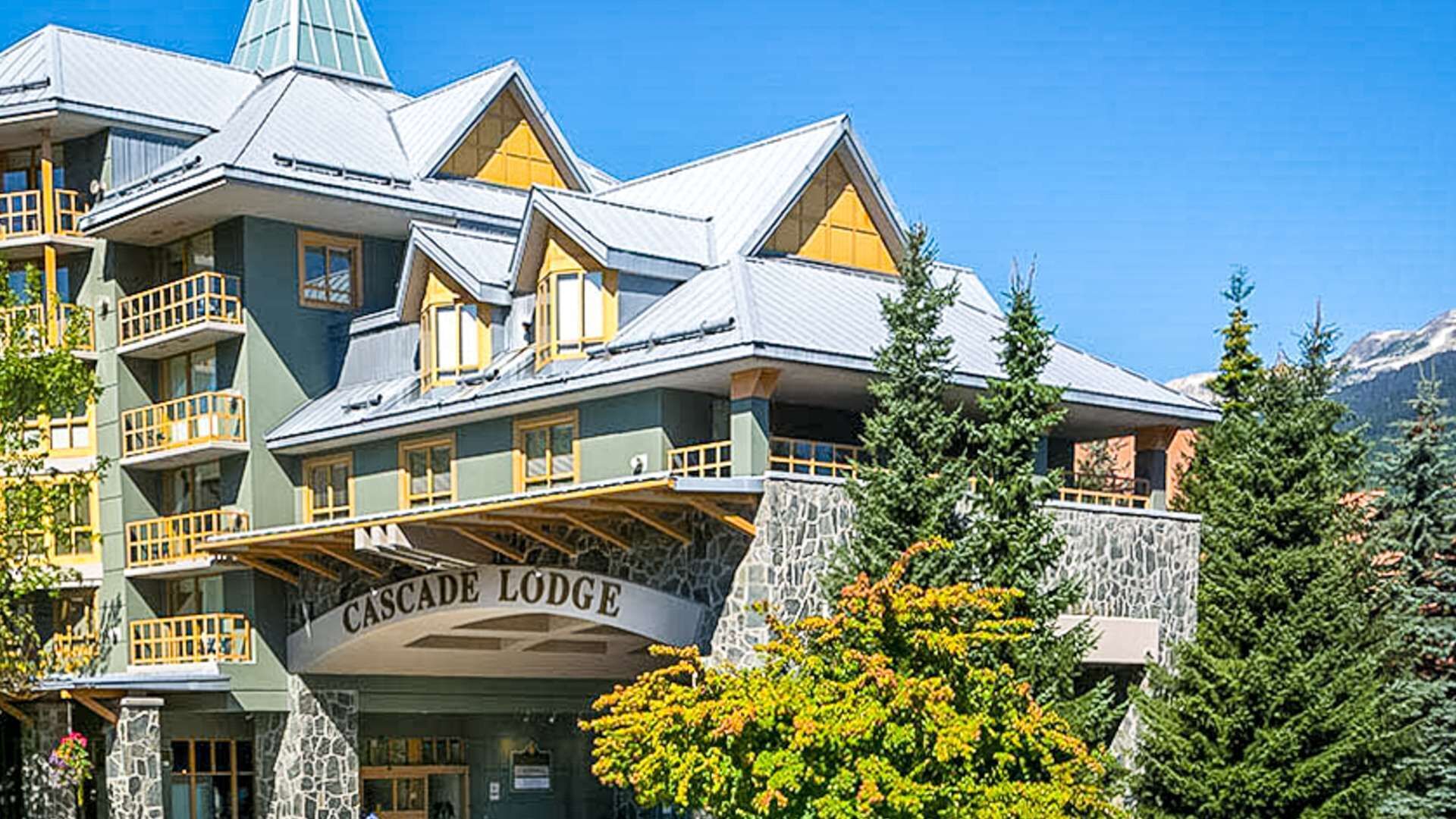 Un edificio de varios pisos con balcones y fachada de piedra, identificado como 'Cascade Lodge'.