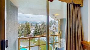 Une pièce dotée d’une grande fenêtre donnant sur un paysage enneigé, une piscine et une vue sur une ville.