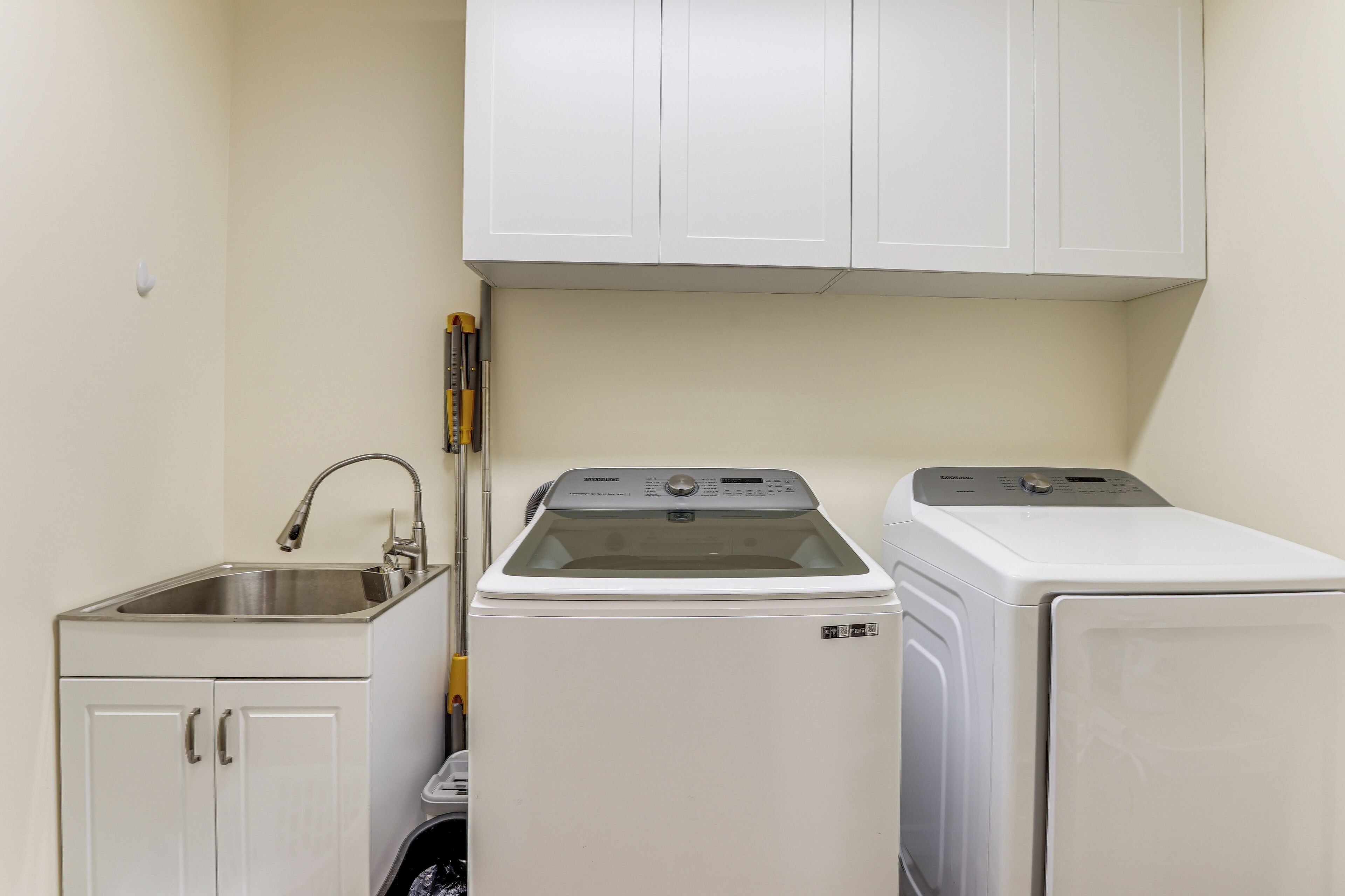 A laundry room with a washing machine, dryer, and sink.