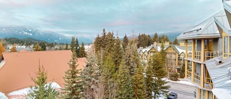 Un hotel con diversi piani, un'area di parcheggio e vista sulle montagne e sugli alberi.
