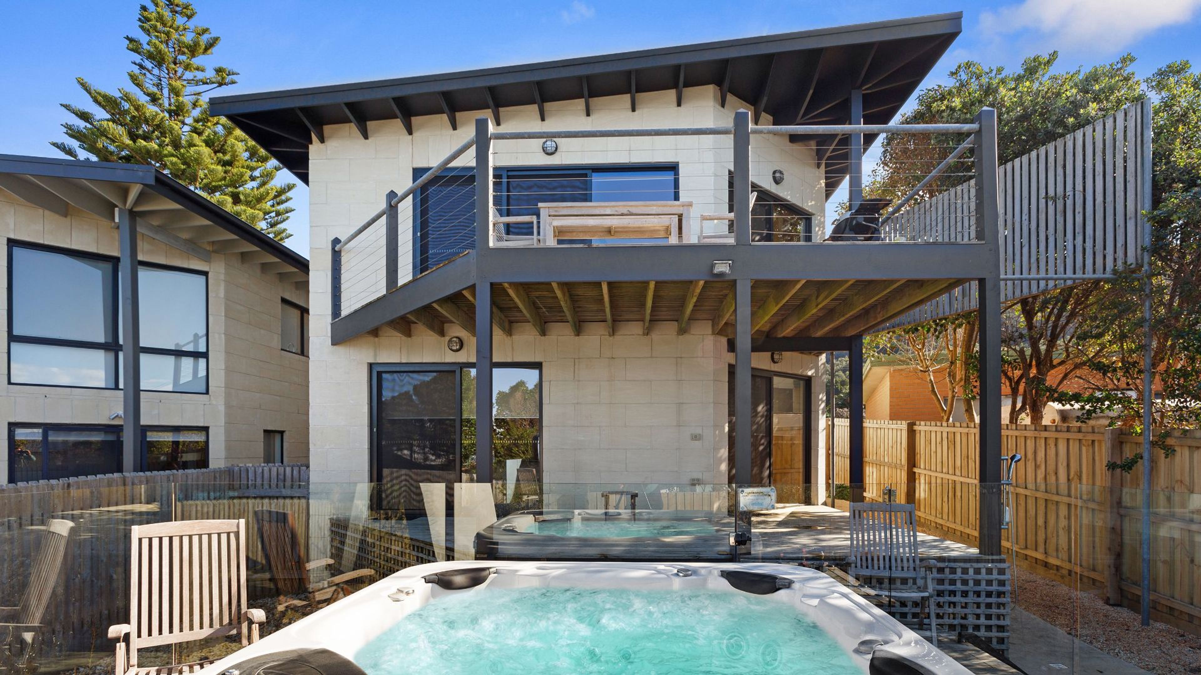 A two-story building with a hot tub area and outdoor seating.
