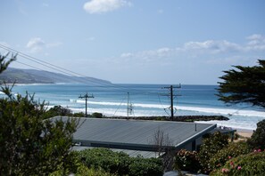 Eine Küstenansicht mit einem Haus im Vordergrund, einem Strand und dem Ozean.