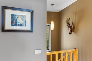 Ein Zimmer mit einem gerahmten Kunstwerk an der Wand, einer Pendelleuchte und einer dekorativen Kopfteil.