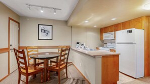 Une cuisine compacte avec des meubles en bois, un réfrigérateur blanc et un petit îlot central doté d’un évier.