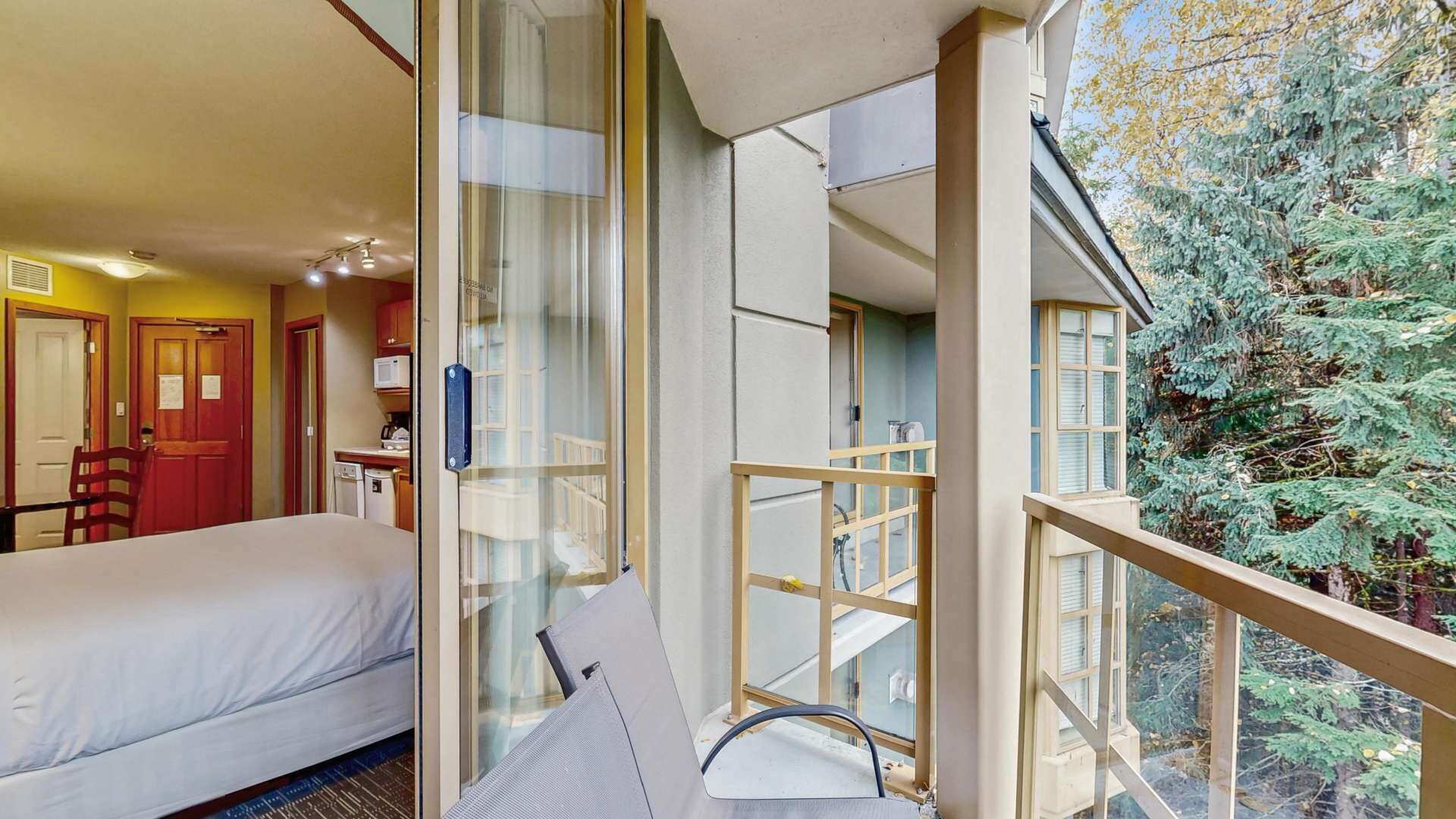 Una habitación de hotel con cama, escritorio, silla y vistas a un árbol.