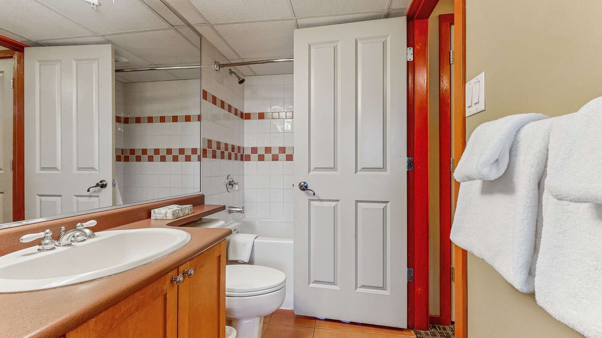 Een badkamer met een wastafel, spiegel, toilet en douche.