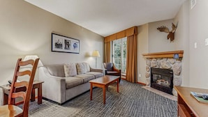 Ein gemütliches Hotelzimmer mit einer Couch, Sesseln, einem Couchtisch, einem Kamin und einem gerahmten Bild an der Wand.