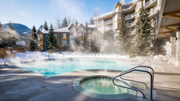 Ein Whirlpool, umgeben von einem Pool, mit einem Gebäude im Hintergrund.