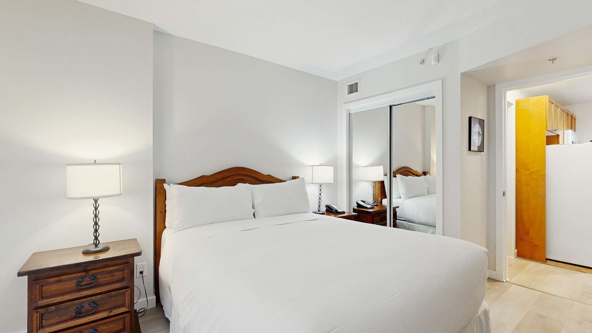 Une chambre d’hôtel avec un grand lit, des lampes de chevet, une table de chevet en bois et un miroir.