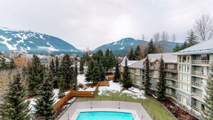 Ein Resort mit Schwimmbad, umgeben von schneebedeckten Bergen und dichten Nadelbäumen.