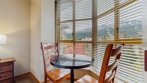 A corner room with a round glass table, two wooden chairs, and a window with blinds. - Whistler - Cascade Lodge 508 (Whistler)