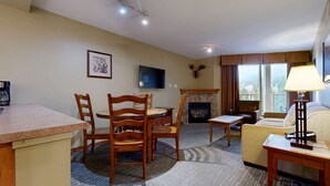 Une chambre d’hôtel avec un coin repas, une cheminée, une télévision et un canapé.