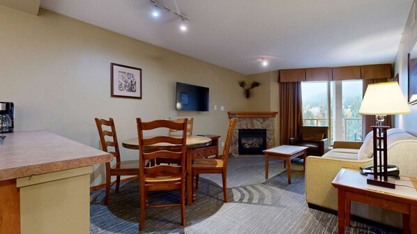 Une chambre d’hôtel avec un coin repas, une cheminée, une télévision et un canapé.