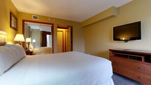 Une chambre d’hôtel avec un grand lit, une télévision, une commode et un miroir.