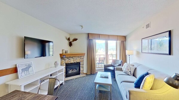 A hotel room with a fireplace, a sofa, a TV, and a dining area. - Whistler - Cascade Lodge 633 (Whistler)