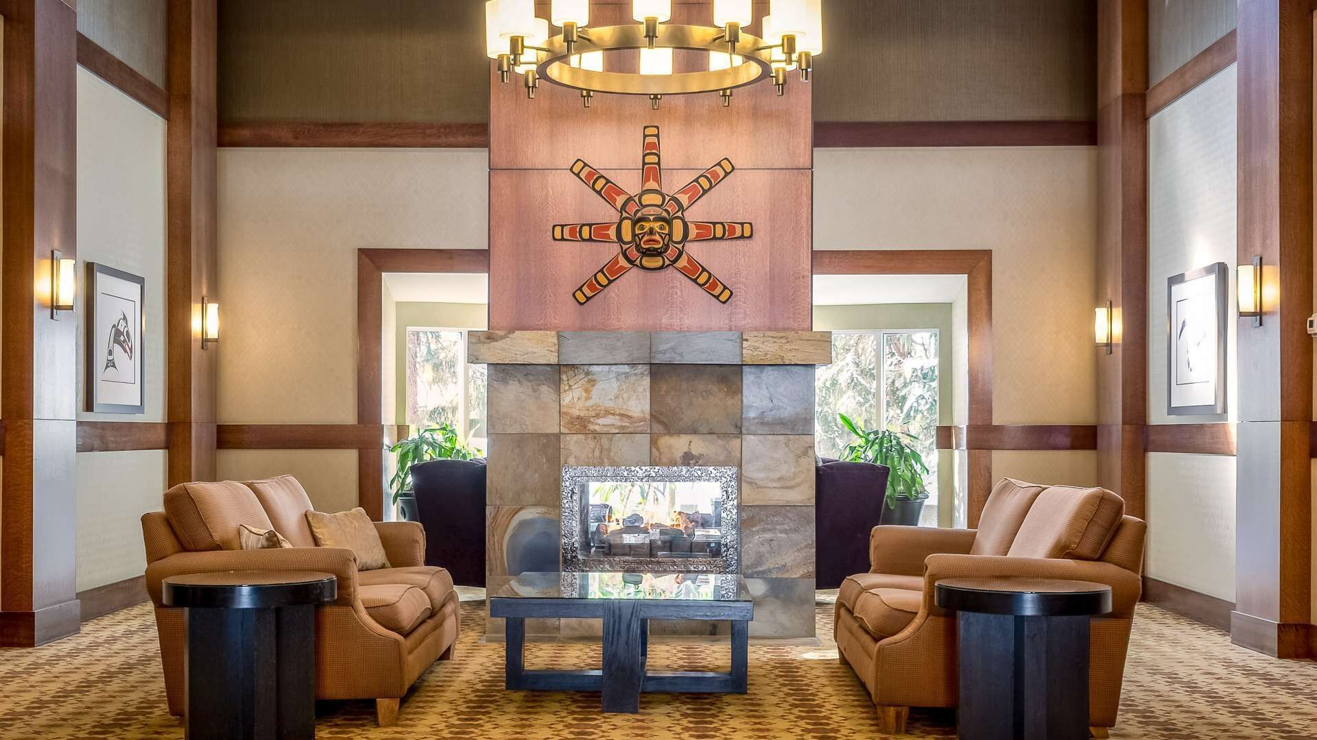 A lobby with a central fireplace, two sofas, and a chandelier.