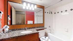 A bathroom with a granite countertop sink, a wooden vanity, a large mirror, a shower with a glass door, and a white toilet. - Whistler - Glacier Lodge 232 (Whistler)