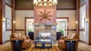 A lobby with two sofas facing a fireplace, framed artwork on the walls, and a chandelier above. - Whistler - Glacier Lodge 252 (Whistler)
