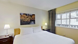A hotel room with a large bed, two bedside tables with lamps, a window with curtains, and a painting on the wall. - Whistler - Glacier Lodge 252 (Whistler)