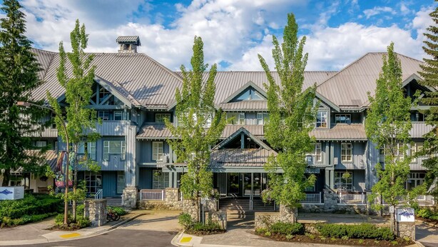 A multi-story hotel with a traditional architectural style, featuring stone foundations and a mix of wood and metal roofing. - Whistler - Glacier Lodge 303 (Whistler)