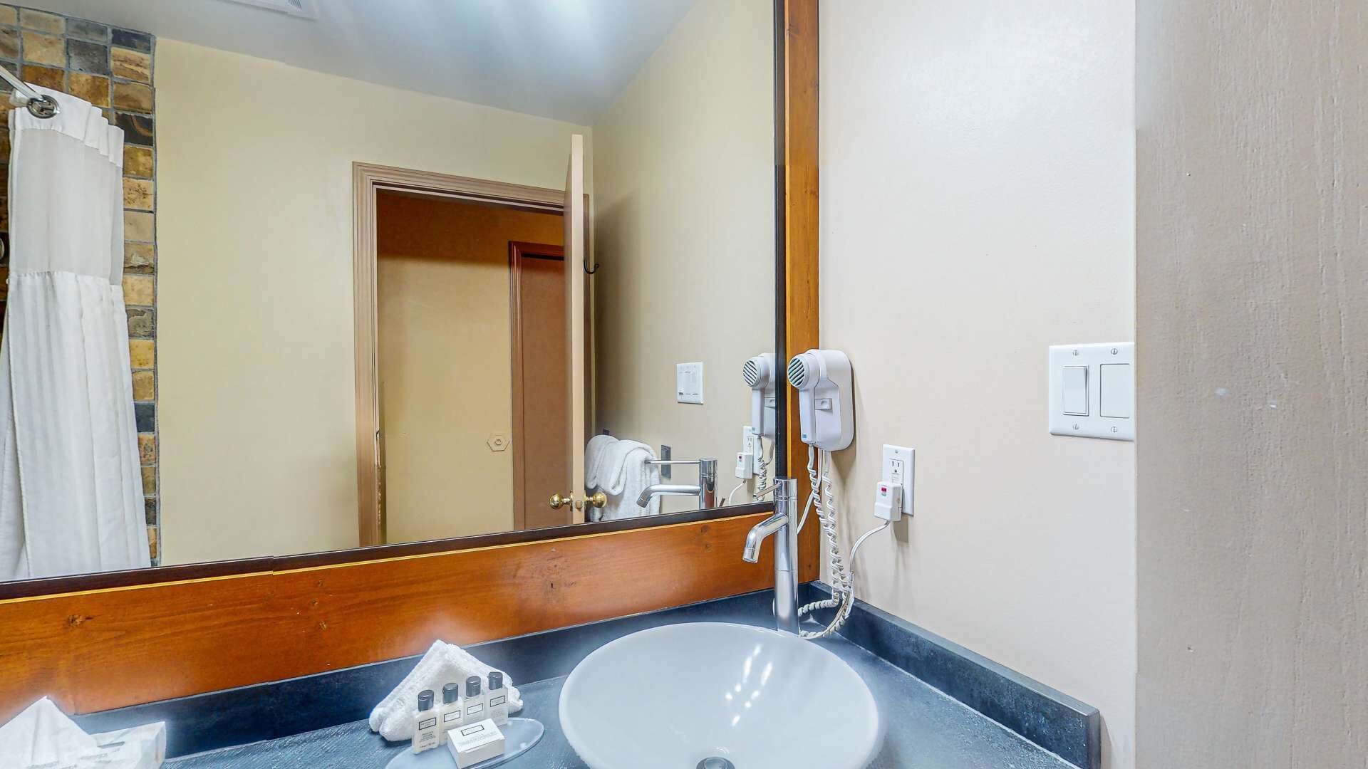 A bathroom with a sink, a hairdryer, and a mirror.