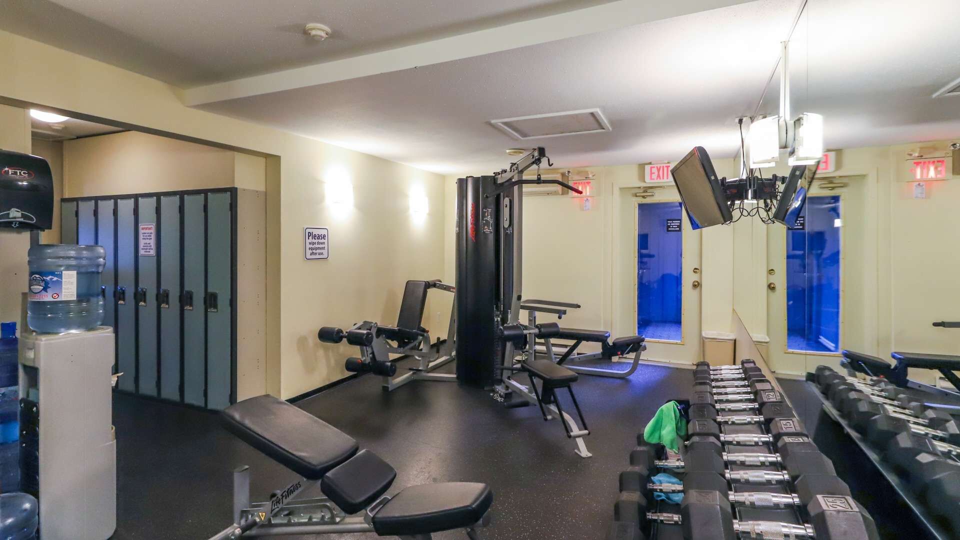 Une salle de sport équipée de bancs, d’haltères et d’appareils de musculation.