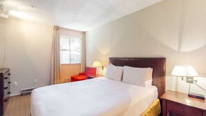 A hotel room with a large bed, a nightstand with a lamp, a red chair, and a window with curtains. - Whistler - Glacier Lodge 341 (Whistler)