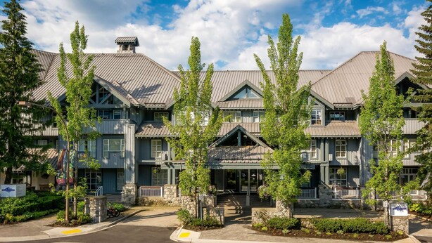 A multi-story hotel with a traditional architectural style, featuring stone foundations and a mix of wood and metal roofing. - Whistler - Glacier Lodge 341 (Whistler)
