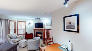 Ein Wohnzimmer mit Kamin, Fernseher und einem gerahmten Kunstwerk an der Wand.