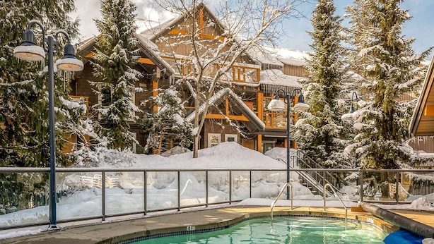 Ein Poolbereich mit Blick auf ein Gebäude mit mehreren Balkonen und schneebedeckten Bäumen.