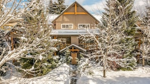 Eine Holzhütte mit steilem Dach, umgeben von schneebedeckten Bäumen.