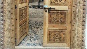 Een houten deur met ingewikkelde gravures en een metalen grendel.