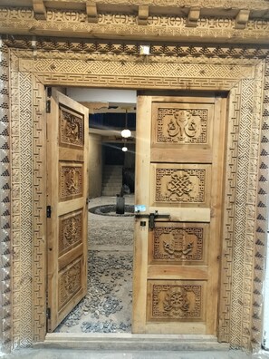 Une porte en bois ornée de sculptures complexes et dotée d’un loquet métallique.