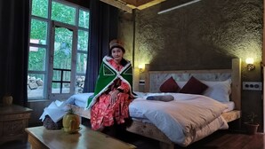 Ein Zimmer mit einem Bett, einem Tisch mit einer Vase und einem Fenster mit Vorhängen.
