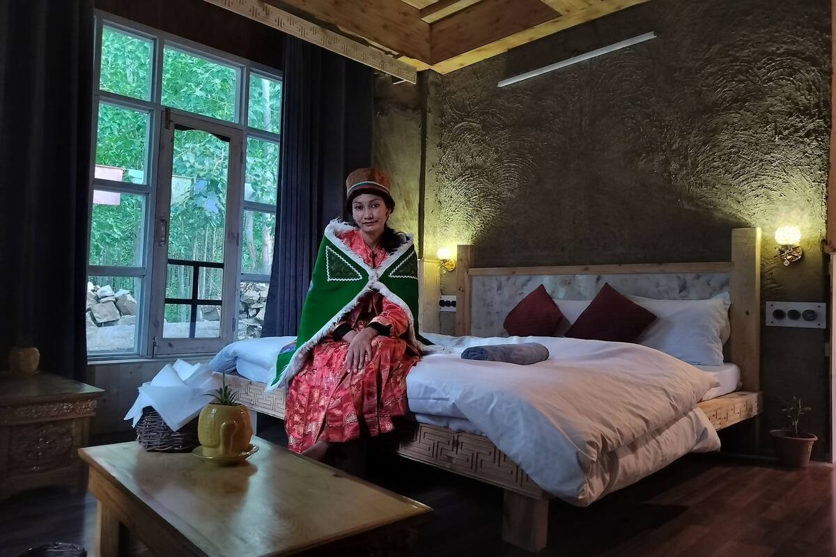 A room with a bed, a table with a vase, and a window with curtains.