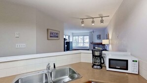 A kitchen with a stainless steel sink, a coffee maker, and a microwave. - Whistler - Marketplace Lodge 338 (Whistler)