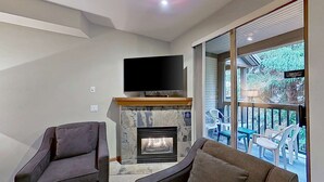 A modern living room with a fireplace, a flat-screen TV mounted above it, and a balcony with outdoor seating. - Whistler - Northstar 93 (Whistler)