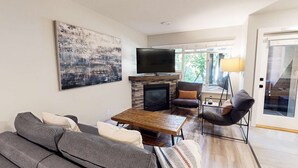 Ein Wohnzimmer mit Kamin, Flachbildfernseher, einer Couch und einem Couchtisch.