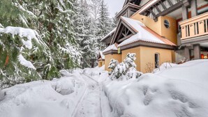 Ein mit Schnee bedecktes Gebäude mit geneigtem Dach, umgeben von schneebedeckten Bäumen.