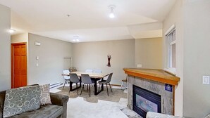 Ein Wohnzimmer mit Kamin, einem Esstisch mit Stühlen, einer Couch und einem Teppichboden.